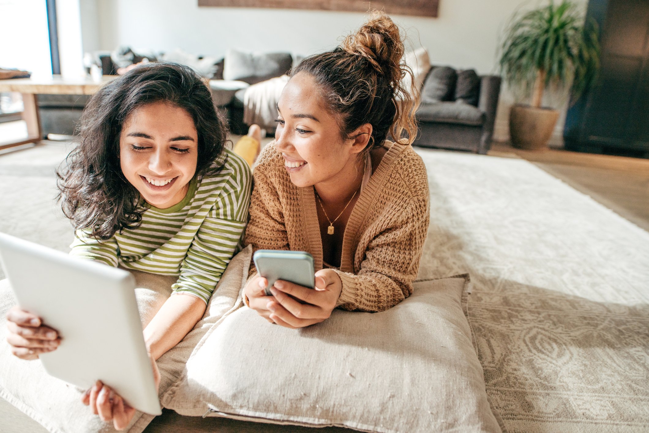 Two female students with digital tablet and cellphone at home