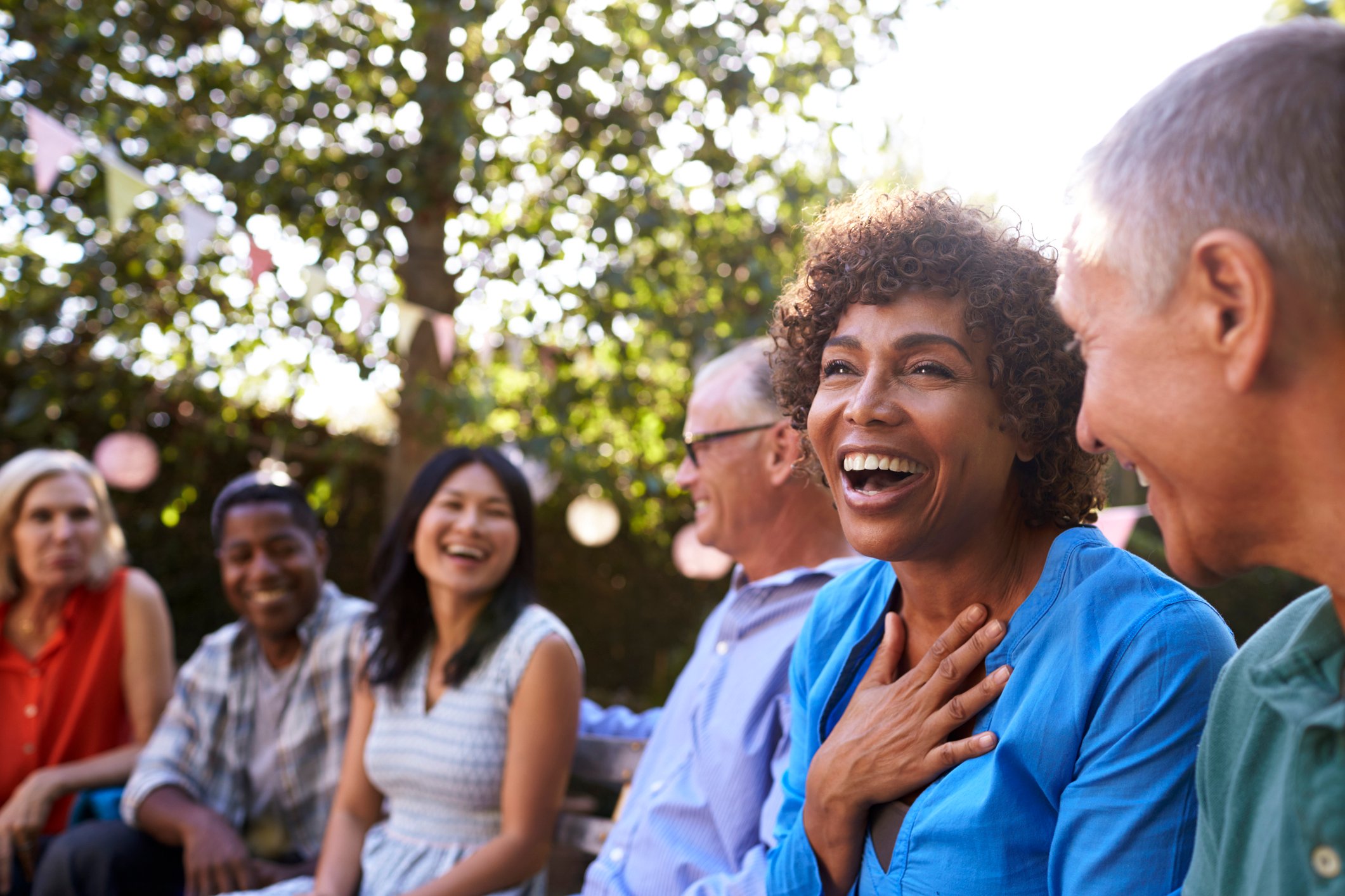 Group Of Mature Friends Socializing In Backyard Together